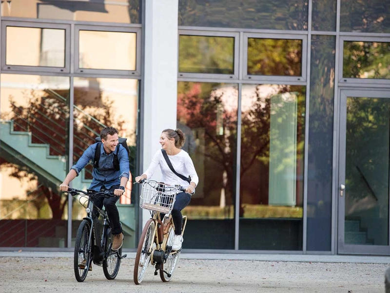 Zwei Radfahrer:innen fahren zufrieden in den Feierabend